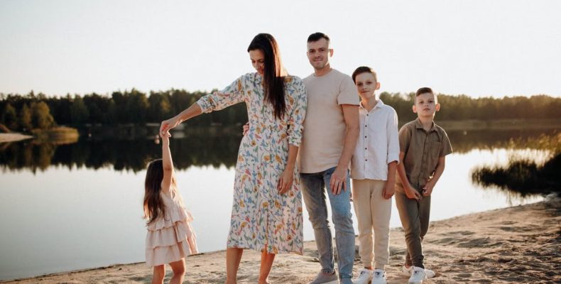 A family of five enjoys a serene lakeside vacation at sunset, capturing precious moments together.